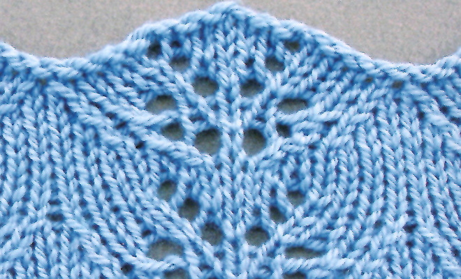 Finished larkspur lace knitting pattern in light blue yarn, showing scalloped Mediterranean flower-inspired stitch pattern