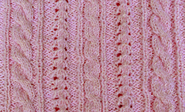 Finished twisted cable rib stitch pattern in pink yarn, showing vertical cables flanked by reverse stockinette ribs with eyelet detail